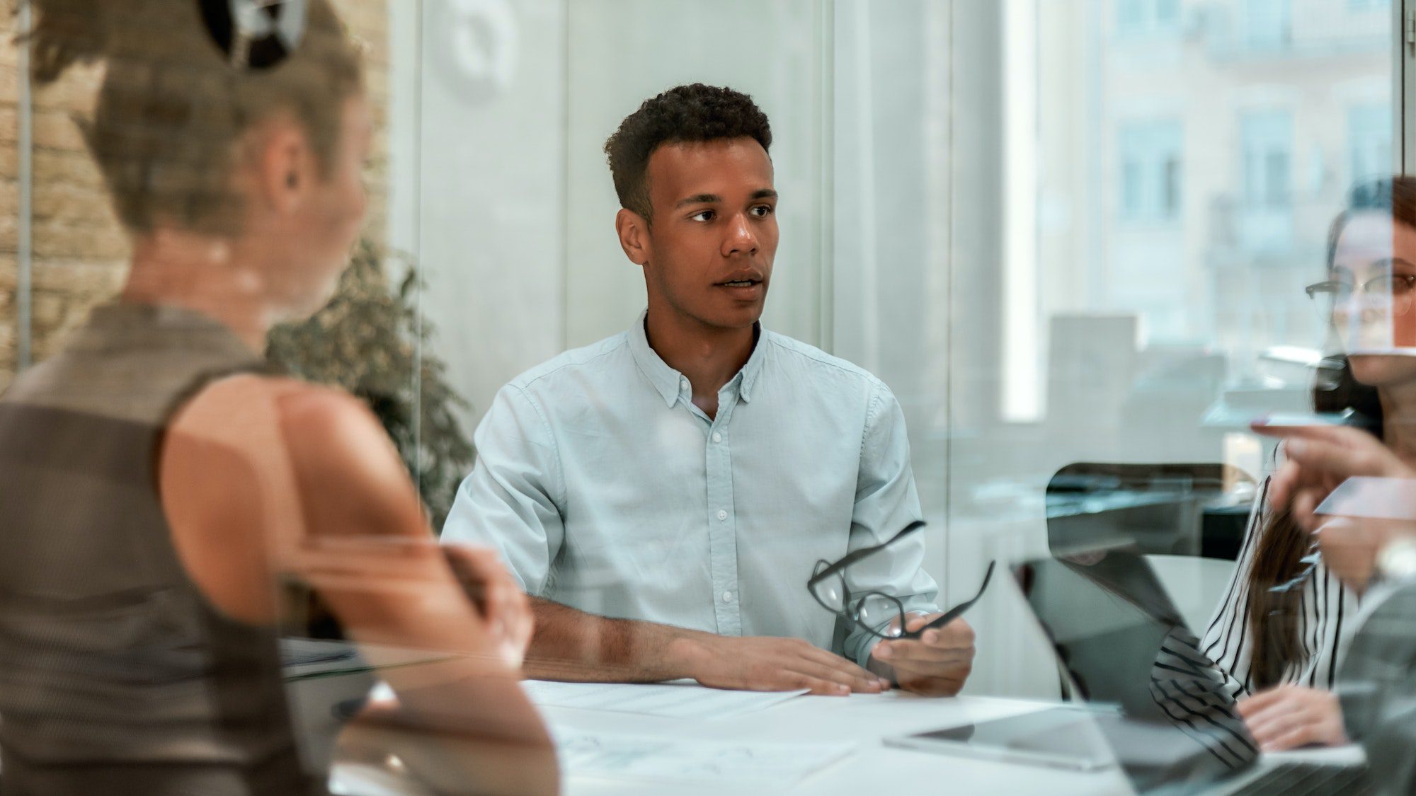 Business expert. Young afro american man holding eyeglasses and explaining something to his